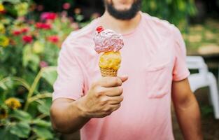 Unrecognizable people holding ice cream in cone outdoors. Front view of person hands holding an ice cream cone. People showing a double ice cream cone. Cone ball ice cream concept photo
