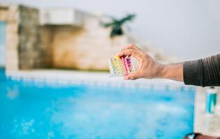 Hand showing tester kit to measure chlorine and ph in swimming pools. Person testing the PH of the swimming pool photo
