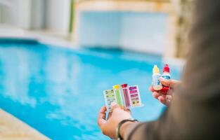 Hand holding tester kit to measure chlorine and ph in swimming pools. Person testing the PH of the swimming pool photo