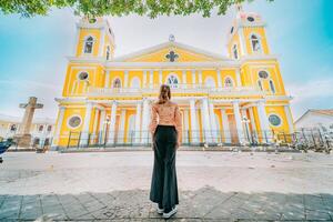 Rear view of a tourist woman in front of a cathedral in a tourist square. Back view of a beautiful tourist in the tourist plaza of Granada, Nicaragua photo