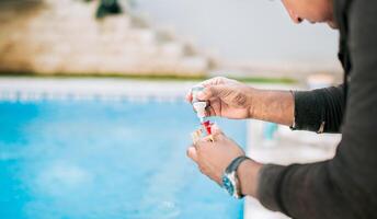 Man using tester kit to measure chlorine and ph in swimming pools. Person testing the PH of the swimming pool photo