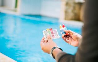 Person testing the PH of the swimming pool. Hand holding tester kit to measure chlorine and ph in swimming pools photo