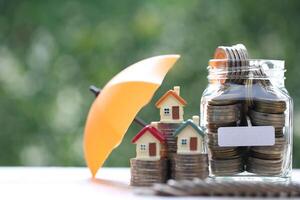 Protection, Model house on stack of coins money with the umbrella on nature green background,Finance insurance and Safe investment concept photo