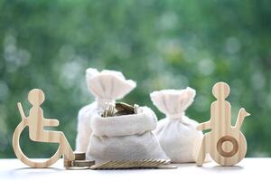 Man on wheelchair and gold coin money in a bag on natural green background,Save money for prepare in future and handicapped person concept photo