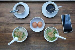 Top view of two cup of coffee and egg with rice porridge on the wooden table for breakfast in the moring photo