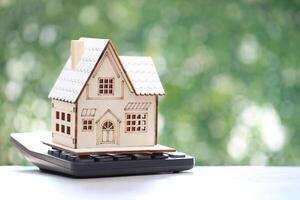 Model house on calculator on natural green background,Business investment and Property tax concept photo