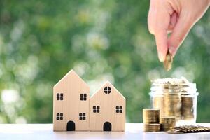 Mortgage,Model house and stack of coins money on natural green background,Business investment and real estate concept photo