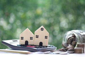 Model house on calculator with stack of coins money on natural green background, Calculating interest payments and Property tax concept photo