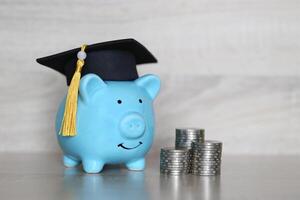 Graduation hat on piggy bank with stack of coins money on wooden background, Saving money for education concept photo