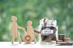 Employee volunteer assistant with man on wheelchair and coin money in the glass bottle on natural green background,Save money for prepare in future and handicapped person concept photo