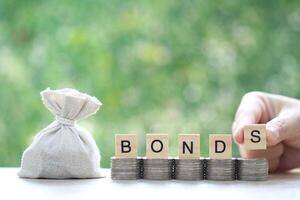 Bonds word on stack of coins money and a bag on natural green background, Investments and Bonds increasing concept photo