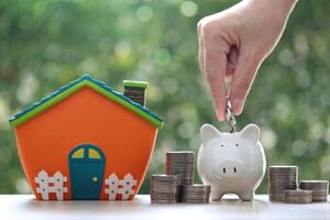 Finance, Model house with piggy bank and stack of coins money on natural green background,Business investment and real estate concept photo