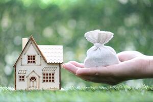 Finance, Model house with money bag on natural green background,Business investment and Save money for prepare in future concept photo