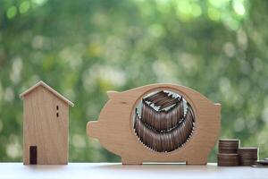 Finance, Model house with piggy bank and stack of coins money on natural green background,Business investment and real estate concept photo