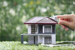 Financial condition, Businesswoman using stethoscope to check model house on natural green background photo