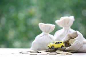 Miniature car model on growing stack of coins money on nature green background, Saving money for car, Finance and car loan, Investment and business concept photo
