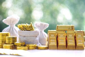 Gold bars and stack of gold coin money in a bag on natural green background,Business investment and financial concept photo