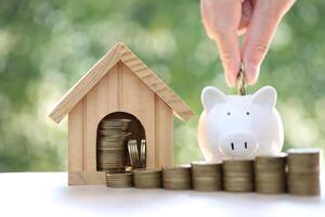 Finance, Model house with piggy bank and stack of coins money on natural green background,Business investment and real estate concept photo