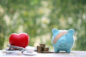 Piggy bank with stethoscope and red heart on green background,Save money for Medical insurance and Health care concept photo