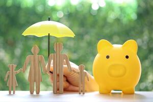 Protection, Model family and hand holding the umbrella with piggy bank on natural green background,Save money for prepare in future and family finance concept photo
