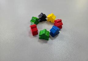 A circle of colorful wooden men on a gray background. Small figures of toy wooden colorful men photo