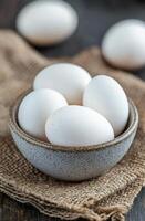 Fresh white eggs in a rustic bowl on burlap fabric photo