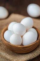 Fresh white eggs in a rustic bowl on burlap fabric photo