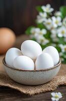 Fresh white eggs in a rustic bowl on burlap fabric photo