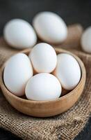 Fresh white eggs in a rustic bowl on burlap fabric photo