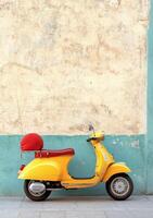 Bright yellow scooter parked against a weathered wall in a charming urban setting photo