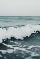 Gentle waves lap against the shore at sunset on a serene beach photo