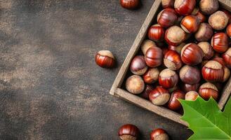Freshly gathered chestnuts in a rustic bowl on a textured surface with autumn leaves photo