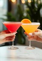 Two friends toasting with colorful cocktails in a trendy bar during the evening photo