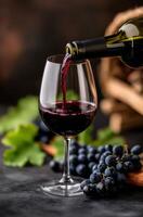 Pouring red wine into a glass beside fresh grapes and autumn leaves photo