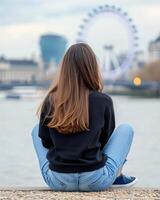 Young woman enjoys sunset view by the River Thames with London Eye in the background photo
