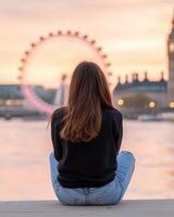 Young woman enjoys sunset view by the River Thames with London Eye in the background photo