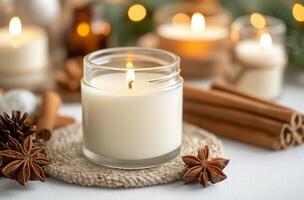 Candle with glowing flame surrounded by cinnamon sticks and festive decorations photo
