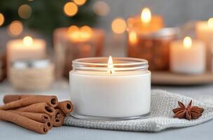 Candle with glowing flame surrounded by cinnamon sticks and festive decorations photo