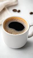 Hot coffee in a white cup with coffee beans floating on the surface photo