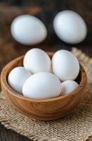 Fresh white eggs in a rustic bowl on a textured burlap cloth photo