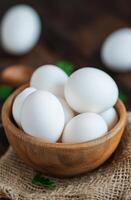 Fresh white eggs in a rustic bowl on a textured burlap cloth photo