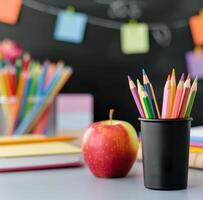 School Supplies With Apple And Colored Pencils On Table Against Blackboard Background photo