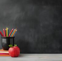 Colorful Pencils and Red Apple on Stacked Books Before Chalkboard photo