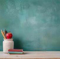 Classroom Desk With Books, Red Apple, And Colorful Pencils On Green Chalkboard Background photo