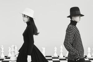 Fashion Models in Black and White Attire on a Chessboard Set photo