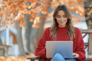 Young Woman Using Laptop and Mobile Phone Outdoors in Autumn photo