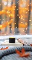 Cozy Bedroom Setting With Candle and Books Surrounded by Autumn Foliage photo