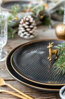 Elegant Holiday Table Setting With Black Plates, Gold Accents, and Pine Decorations photo