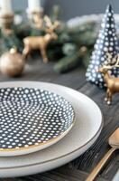Elegant Holiday Table Setting With Black Plates, Gold Accents, and Pine Decorations photo