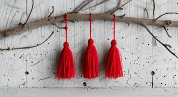 Red Decorative Tassels Hanging on a Branch Against a Rustic White Background photo